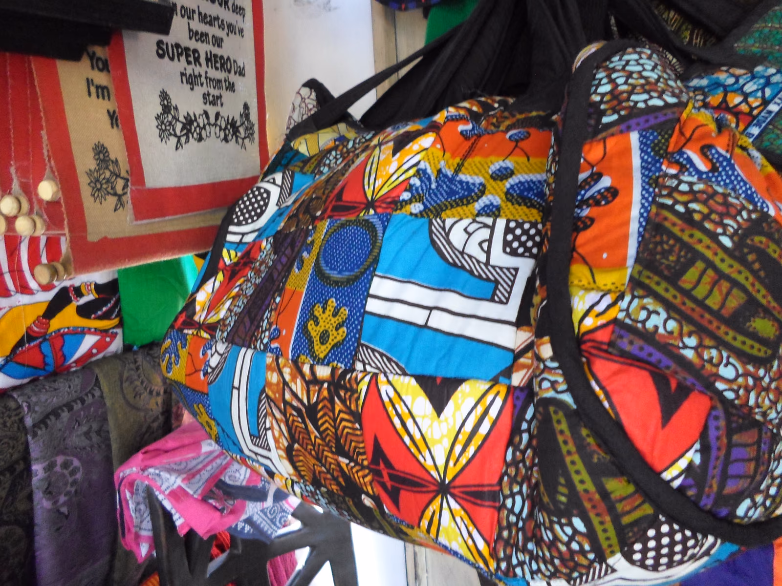 Bags sewn from kitenge, the printed cloth showing bold blocks of colour and repeating geometric motifs.
